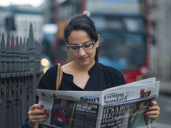 Genç kız Londra'da ücretsiz gazete okuyor