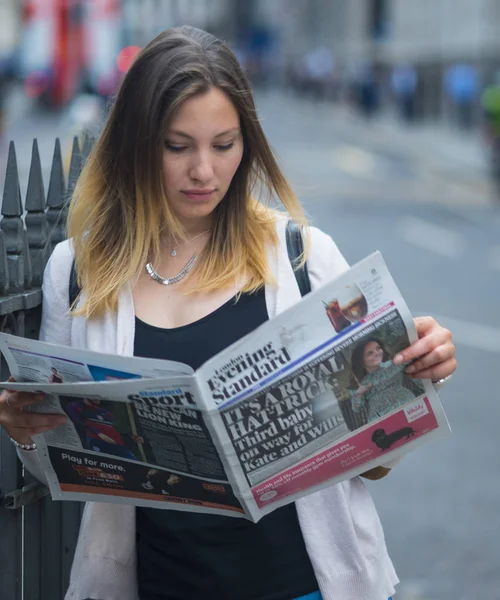 Beautiful young woman reads the newspaper in London — Stock Photo, Image