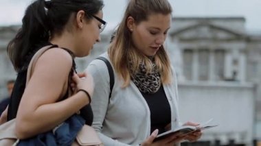 İki genç kadın bir Seyahat Rehberi şehir gezisi sırasında okuyun.