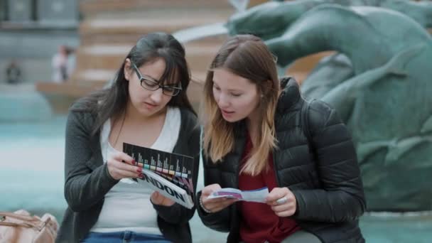 Dos chicas leen una guía de viaje en el centro de Londres — Vídeo de stock