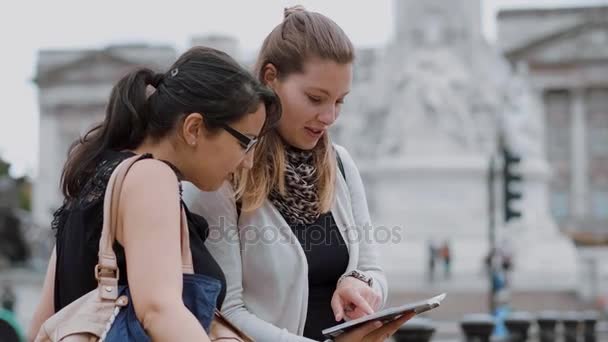 Duas jovens mulheres lêem em um guia de viagem durante uma viagem à cidade — Vídeo de Stock