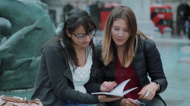 Duas meninas lêem um guia de viagem no centro da cidade de Londres — Vídeo de Stock