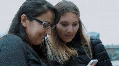 İki kız fotoğrafları cep telefonu seyretmek