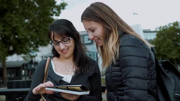 Two girls read a travel guide in the city center of London — Stock Video