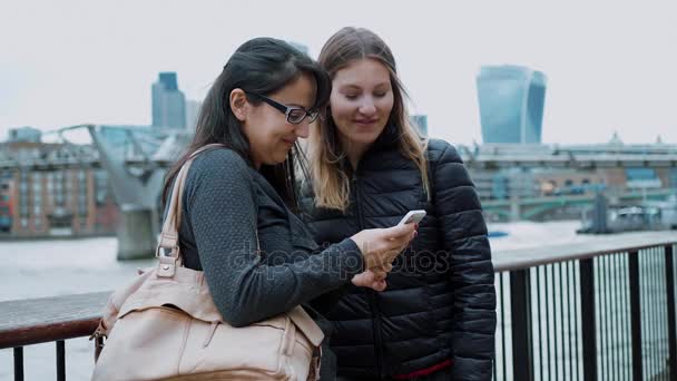 Две девушки смотрят фотографии на мобильном телефоне — стоковое видео