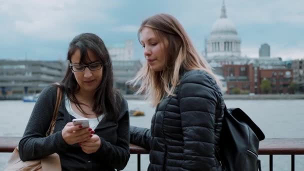 Две молодые женщины на берегу Темзы в Лондоне — стоковое видео