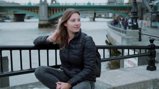 20-jähriges Mädchen sitzt auf Mauer und verliert sich in Gedanken — Stockvideo