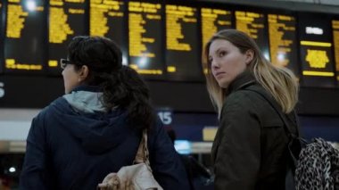 İki kız bir tren istasyonunda kalkış tablo kontrol