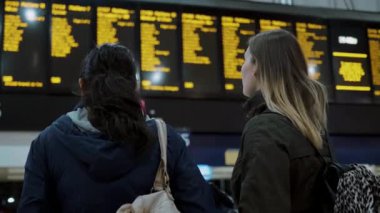Kalkış saatleri kontrol bir tren istasyonunda iki genç kadın