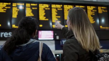 İki kız bir tren istasyonunda kalkış tablo kontrol