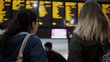 Kalkış saatleri kontrol bir tren istasyonunda iki genç kadın