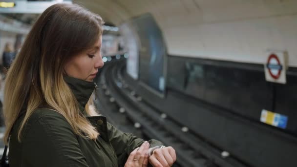 Ung kvinna väntar på Londons tunnelbana röret — Stockvideo