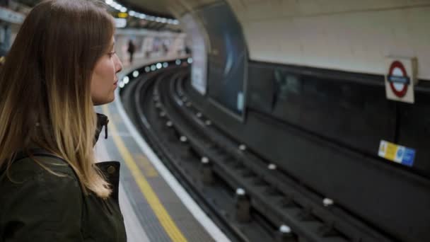 Jonge vrouw wacht op de metro van Londen aan buis — Stockvideo