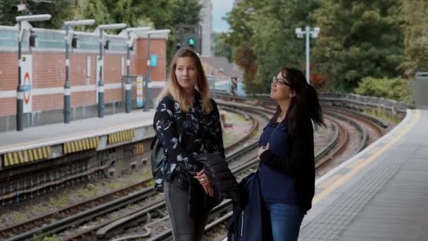 Dos jóvenes esperan el metro en la estación de metro de Londres — Vídeos de Stock