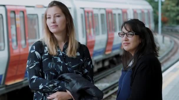 Dos jóvenes esperan el metro en la estación de metro de Londres — Vídeo de stock