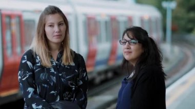 İki genç kadın Londra metro istasyonunda metro bekleyin