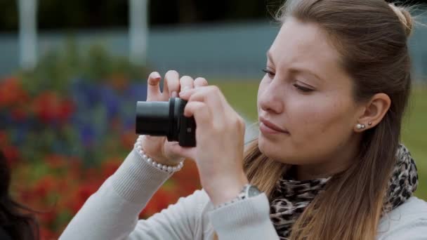 Молодая девушка фотографируется в парке — стоковое видео