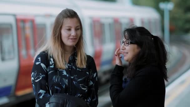 İki genç kadın Londra metro istasyonunda metro bekleyin — Stok video