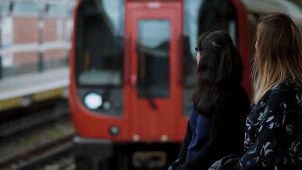 İki genç kadın Londra metro istasyonunda metro bekleyin — Stok video