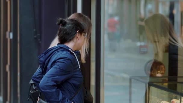 Duas garotas olham uma vitrine em uma milha de compras — Vídeo de Stock