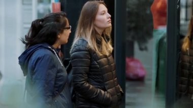 İki kız bir dükkan pencere üzerinde alışveriş caddesine bak.