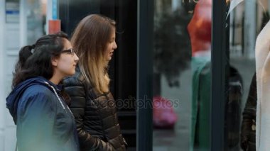 İki kız bir dükkan pencere üzerinde alışveriş caddesine bak.
