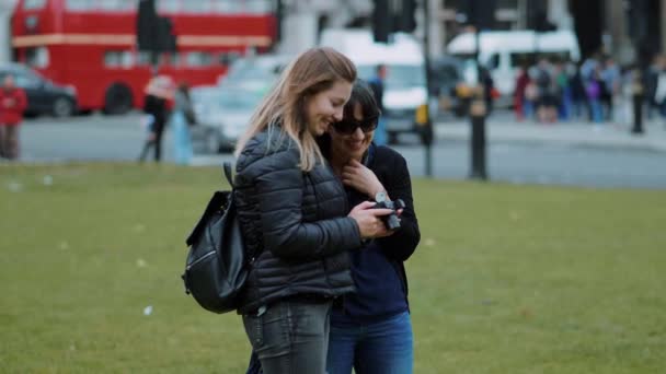 Dos mujeres jóvenes revisan fotos en la cámara - Londres turismo en cámara lenta — Vídeos de Stock