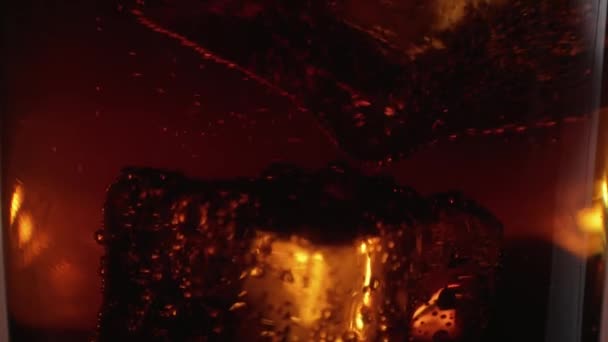 Les gros glaçons flottent dans un verre de Cola - gros plan macro au ralenti 