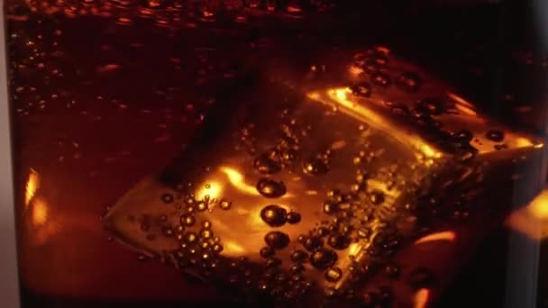 Flytande isbitar i ett glas Cola - närbild makro skott i slow motion — Stockvideo