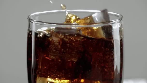 Erstaunliche Nahaufnahme eines Glases Cola mit Eiswürfeln - erfrischende Limonade in Zeitlupe — Stockvideo