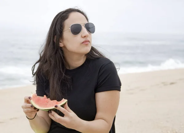 아름다운 여인 이 해변에서 수박을 먹고 있다 — 스톡 사진