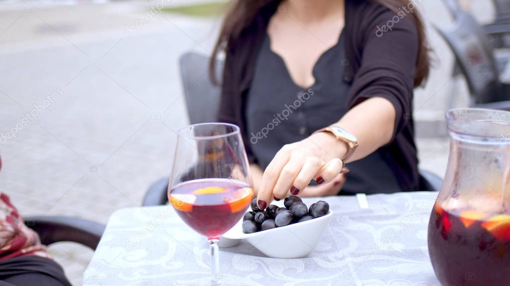 Young woman eats olives in a street restaurant