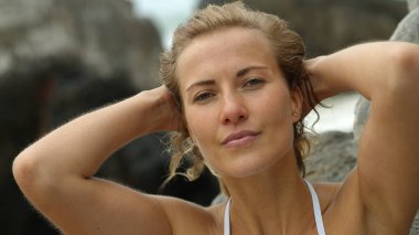 Güzel bir kadın, okyanusta bir sahilde kameraya poz veriyor. Seyahat fotoğrafçılığı.