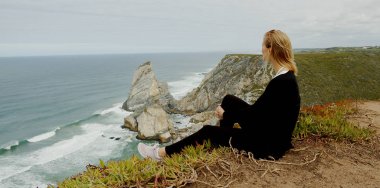 Young woman enjoys the view over the ocean at Cabo da Roca in Portugal - travel photography clipart