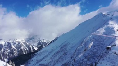 Flight over snow-capped mountains in the Swiss Alps on a winters day - aerial footage