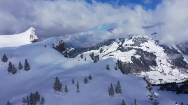 Flight over snow-capped mountains in the Swiss Alps on a winters day - aerial footage