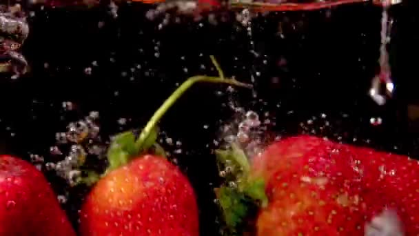 Fresas frescas cayendo en el agua - cámara lenta — Vídeo de stock