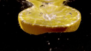 Bir portakalın dilimi yavaş çekimde suya düşüyor.