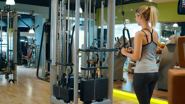 Тренировка мышц в тренажерном зале - девушка занимается спортом — стоковое фото