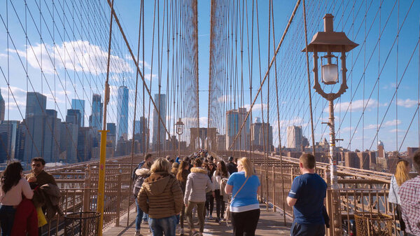Tourists walking over the Brooklyn Bridge in New York - NEW YORK CITY, UNITED STATES - APRIL 2, 2017