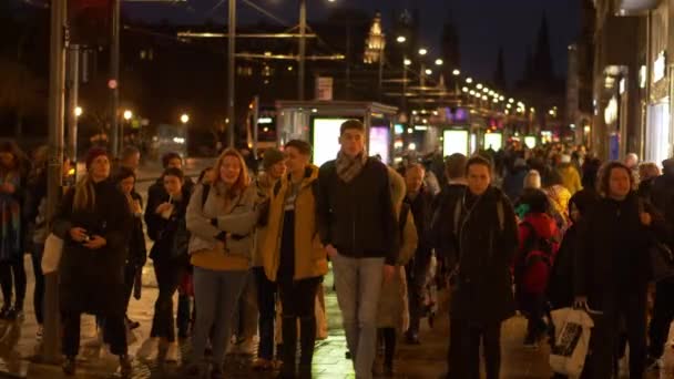 Пешеходы, идущие ночью по Принсес-стрит в Эдинбурге — стоковое видео