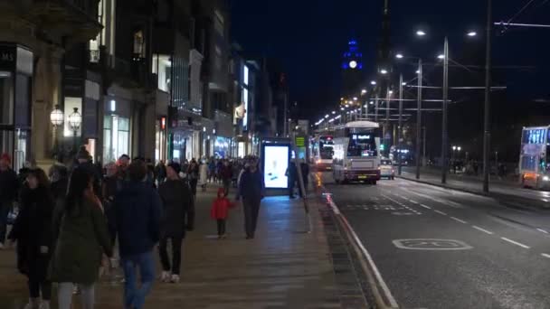 Пешеходы, идущие ночью по Принсес-стрит в Эдинбурге — стоковое видео