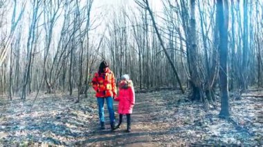 Anne ile kızı bahar ormanda güneşli ışınları ile yürüme