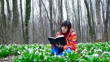 Akıllı bir güzel kız çiçek açması kardelen tam bir bahar ormanda ilginç bir kitap okuma