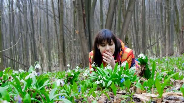 En vacker kvinna har blommande snödroppar i en våren skog — Stockvideo