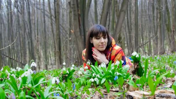 En vacker kvinna har blommande snödroppar i en våren skog — Stockvideo