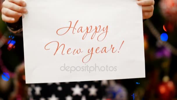 Two childs hands hold a piece of paper with a congratulation happy new year — Stock Video