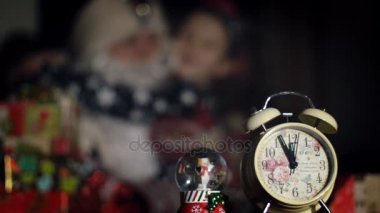 Alacakaranlık gece ön planda bir çalar saat, arka planda bir sevimli küçük kız Noel Baba hugs