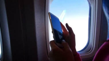 Görünüm uçak penceresinden çalışma bir gadget'ı, smartphone, cep telefonu, parmak hareketi eller karanlık siluet görebilirsiniz. Görünür gökyüzü, bulutlar, hava açık, güneşli gün