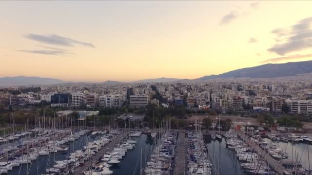 Amanecer en el puerto deportivo griego, Atenas. Grabación de video Aero. Muchos yates diferentes, catamaranes amarrados a muelles. En el fondo se encuentra el paisaje de las montañas y las casas de la ciudad. Verano claro — Vídeo de stock